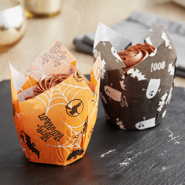 A Baker's Mark Halloween tulip baking cup with a spider web design holding a cupcake.