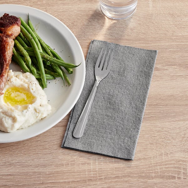 A plate of food with a fork and a Touchstone by Choice black linen-feel dinner napkin.