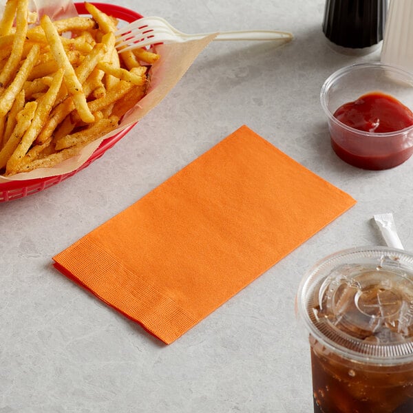 A table with a basket of fries, a plastic cup of brown liquid, and a Choice orange paper napkin next to a drink.