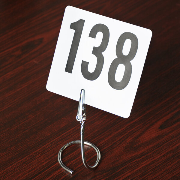 An American Metalcraft stainless steel alligator clip card holder with a white sign and black numbers.