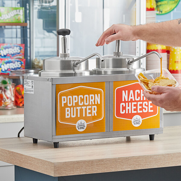 A person using a Carnival King double warmer to pour cheese sauce onto nachos.
