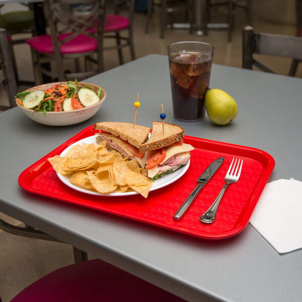 A red Carlisle fast food tray with a sandwich and chips on it.