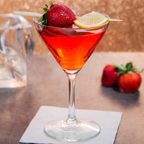 A Libbey martini glass filled with red liquid and garnished with a strawberry and lemon slice.