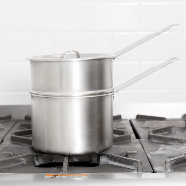 A Vollrath stainless steel double boiler set on a stove.