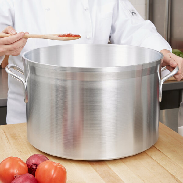 A woman using a Vollrath Wear-Ever Classic Select sauce pot to cook tomatoes and onions.