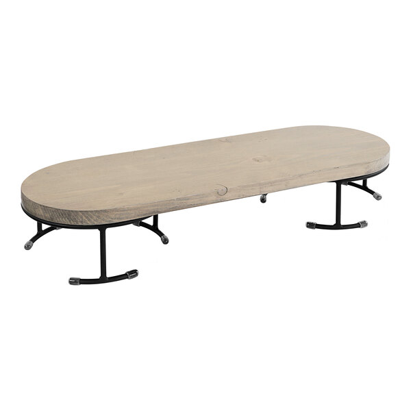 A Cal-Mil gray-washed pine wood display riser with removable metal legs on a wooden table with black metal legs.