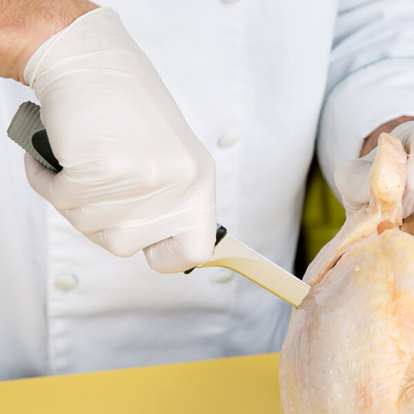 A person wearing white gloves using a Dexter-Russell V-Lo narrow boning knife to cut chicken.