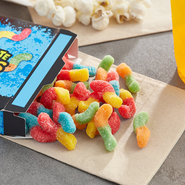 A box of Trolli Mini Sour Brite gummy worms on a table in a stadium concession stand.