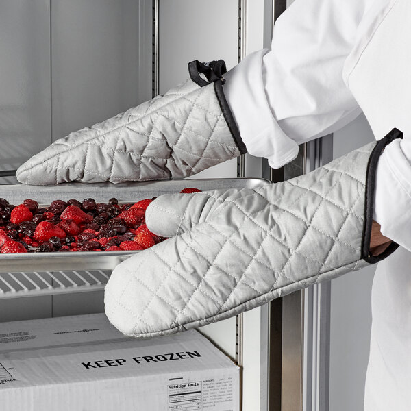 A person wearing San Jamar silicone-coated oven mitts holding a tray of berries.