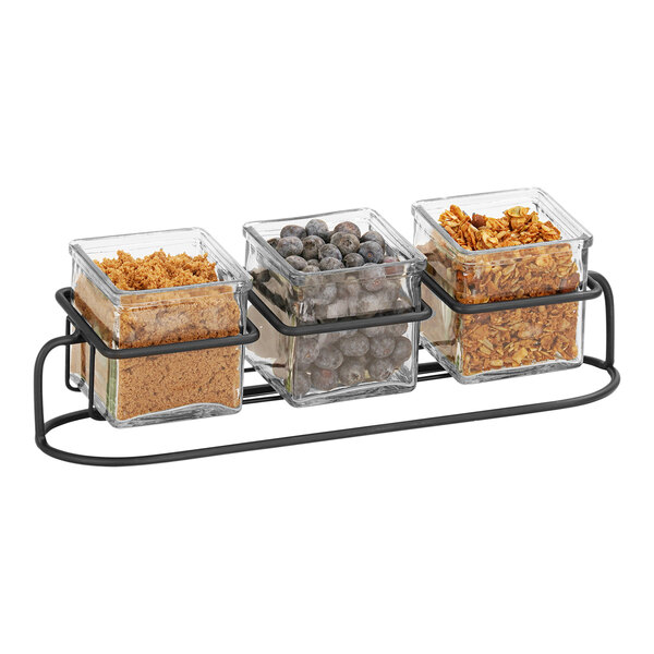 A Cal-Mil black metal rack holding three glass jars with nuts and seeds.