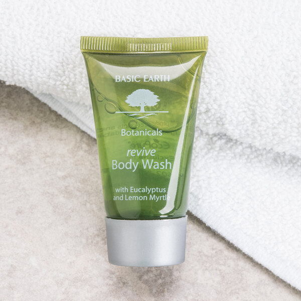 A green bottle of Basic Earth Botanicals body wash on a white surface.
