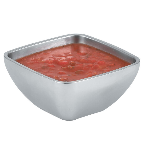 A Vollrath square metal bowl filled with red sauce on a table.