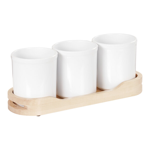 A wooden tray with three white containers on it.