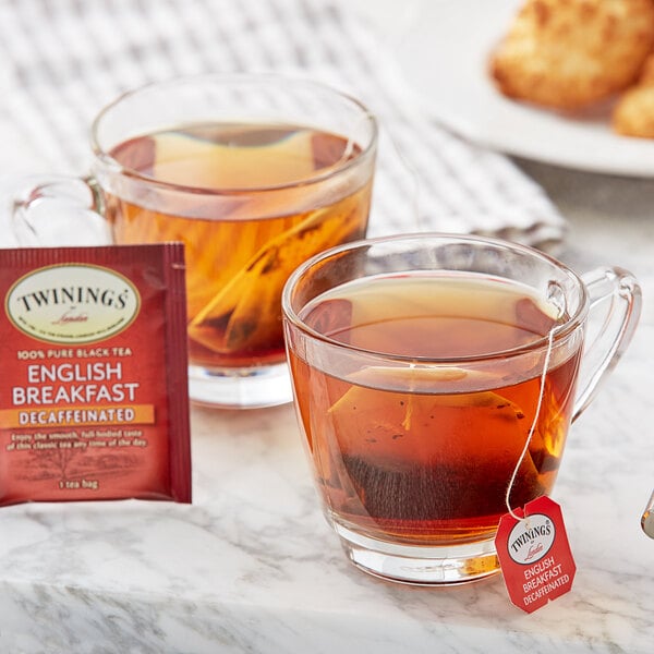 A glass cup of Twinings decaffeinated English breakfast tea with a tea bag next to a cup of tea.