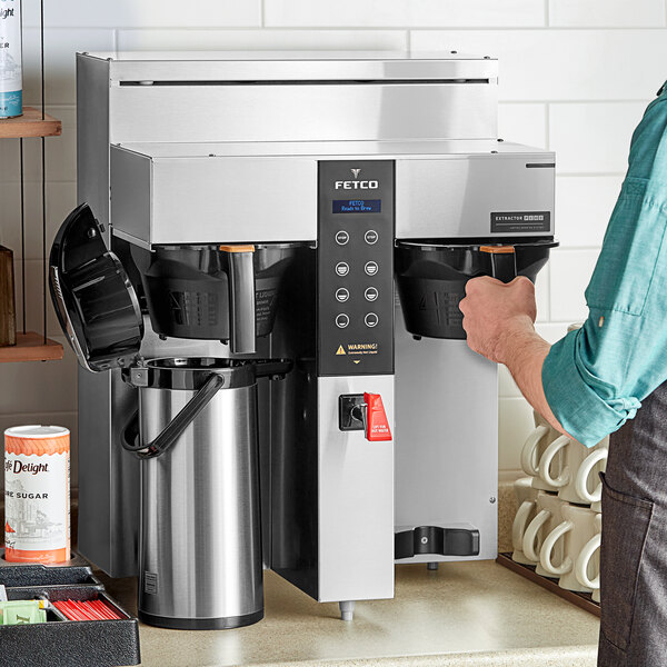 A person using a Fetco CBS-1232 coffee machine to brew coffee.