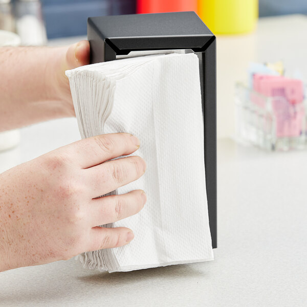 A person pulling a Dixie Basic white tall-fold dispenser napkin from a box.
