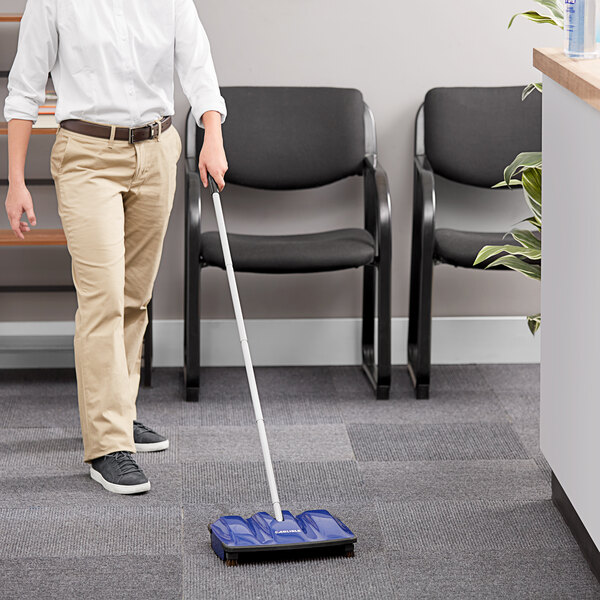 A woman using a Carlisle Duo-Sweeper to sweep the floor in a corporate office.