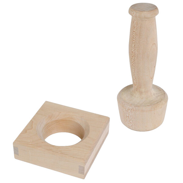 A wooden block with a hole in it and a wooden handle inserted into a circular object.