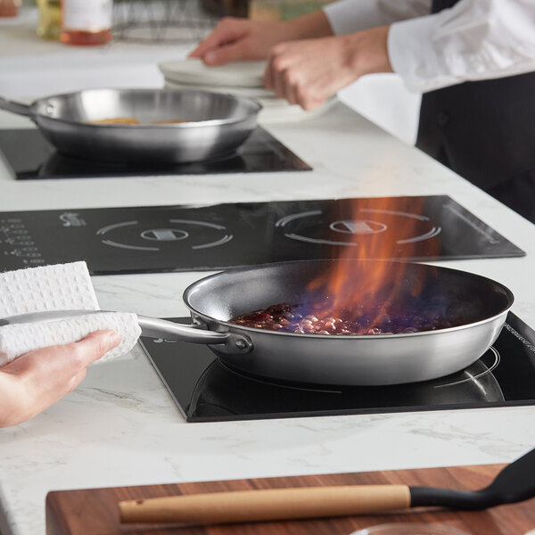 A person cooking with a Vigor Tri-Ply Stainless Steel Non-Stick Fry Pan on a stove.