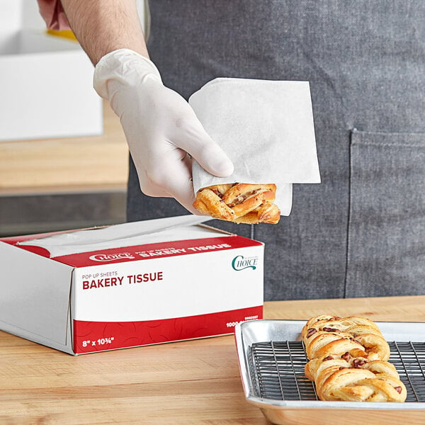 A person wearing gloves holding food and putting it into a box.