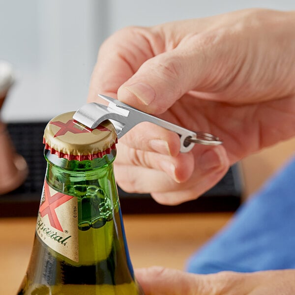 A hand using a Choice silver aluminum bottle opener to open a bottle of beer.