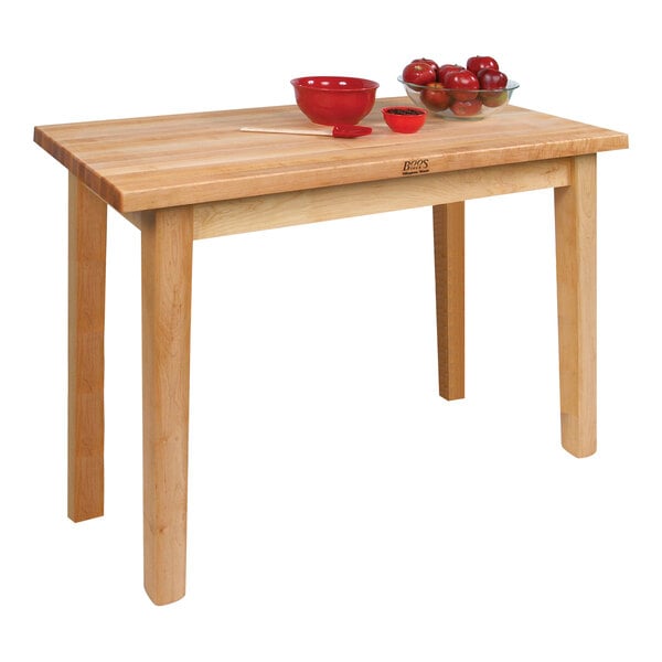 A John Boos natural maple wood work table with a bowl of apples and a bowl of sauce.