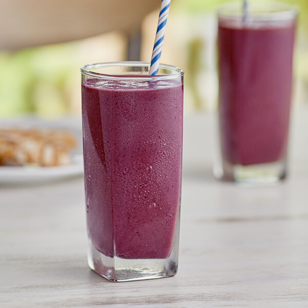 A glass with a straw in a purple smoothie made with Tropical Acai Organic Sweetened Acai Blender Cubes.