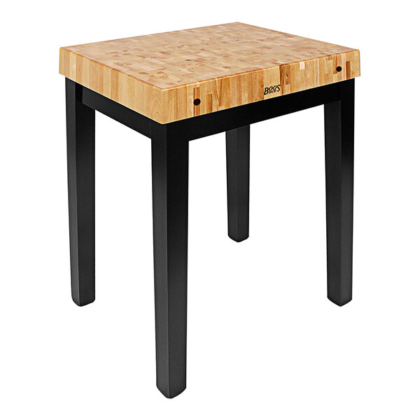 A John Boos black maple chef's block on a wooden table with black legs.