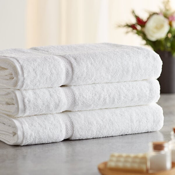 A stack of three white Lavex Premium bath sheets on a white surface.