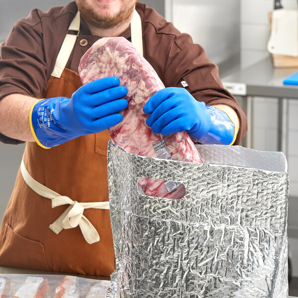 A man wearing blue Ansell AlphaTec PVC gloves and a blue apron holding a piece of meat.