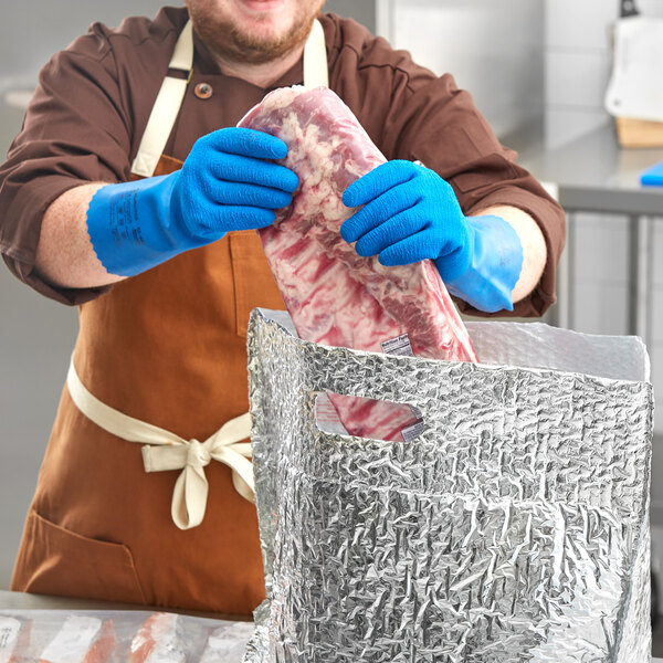 A man in blue Ansell AlphaTec rubber gloves holding a piece of meat.
