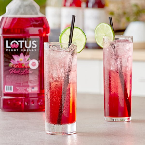 A glass of pink Lotus energy drink with a straw and lime slice.