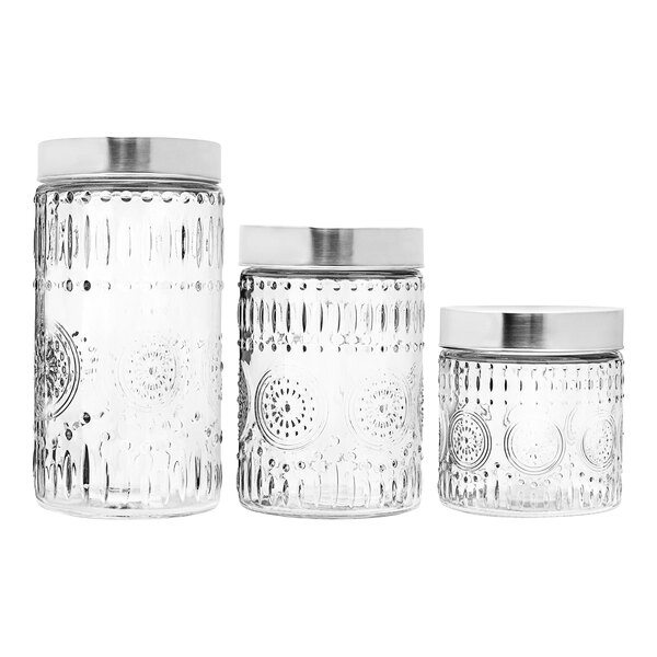A group of three clear glass canisters with stainless steel lids.