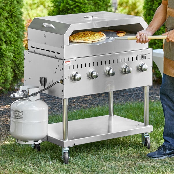 A man cooking pizza on a Backyard Pro stainless steel grill.