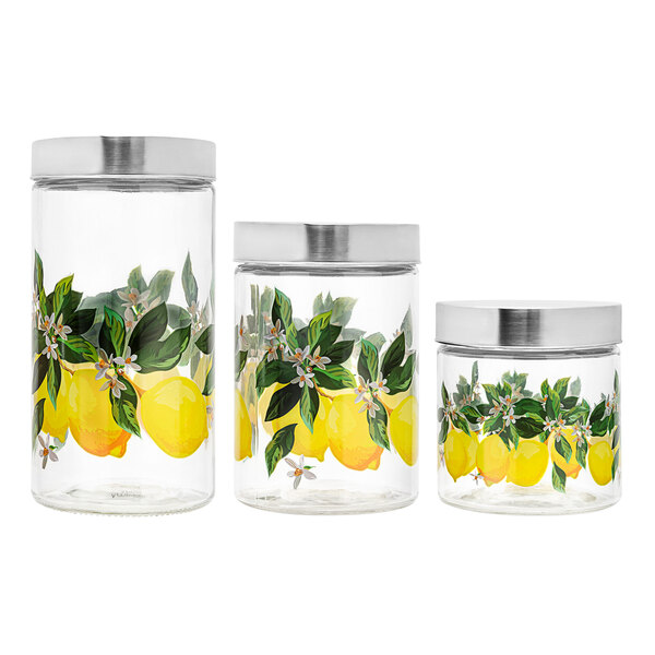 Three glass jars with lids, one of which has lemons and leaves painted on it.