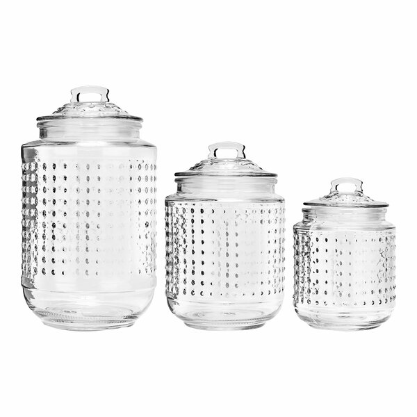 A group of clear glass canisters with glass lids.
