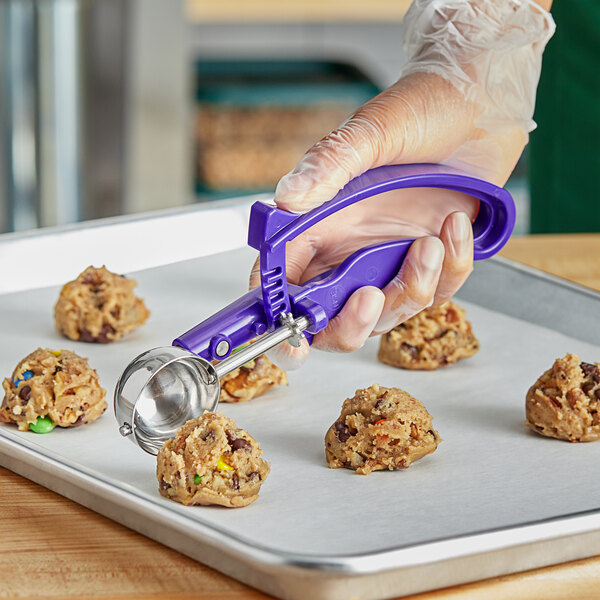 A person using a purple EZ grip disher to scoop food.