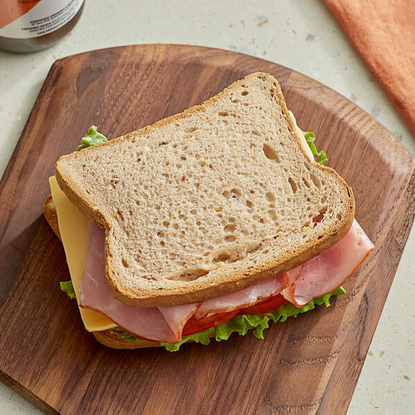 A sandwich on a wooden cutting board with Little Northern Bakehouse Gluten-Free Wide Slice Whole Grain Bread.