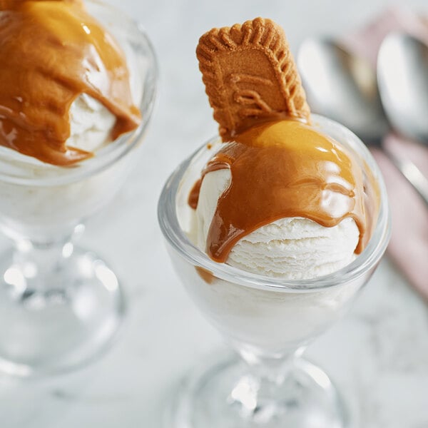 A scoop of Lotus Biscoff cookie butter ice cream with caramel sauce in a glass cup.