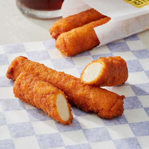 A close-up of RollerBites Buffalo Ranch Chicken sticks on a checkered paper.