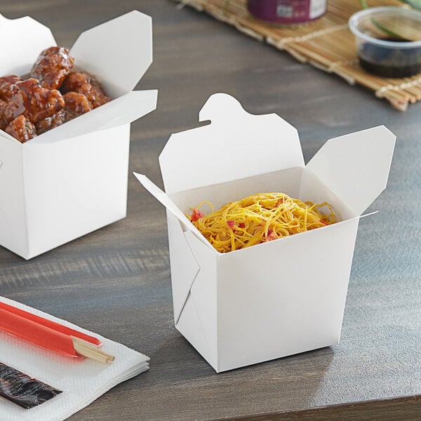 Two Emperor's Select white microwavable take-out containers on a table with chopsticks.