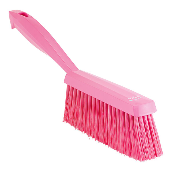 A pink Vikan hand brush with a long handle.