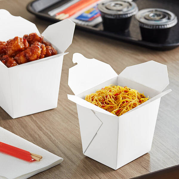 Two Emperor's Select white take-out containers filled with food on a table.