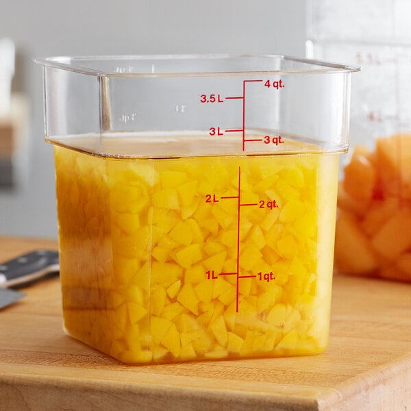 A Cambro square clear polycarbonate food storage container with yellow liquid inside.
