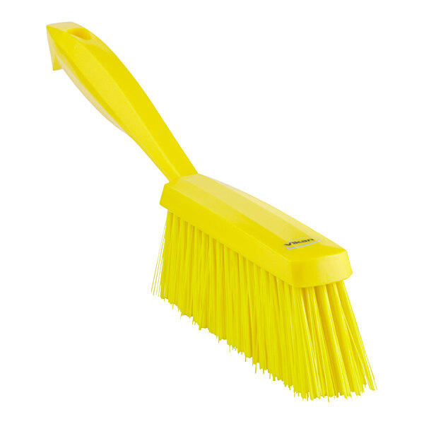 A close-up of a yellow brush with a long handle.
