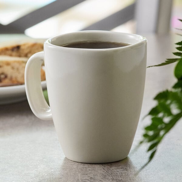 A white Tuxton Safari china mug with brown liquid in it.