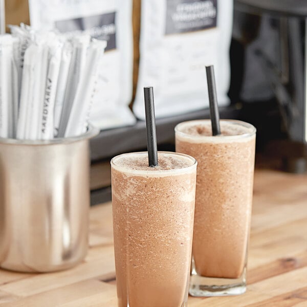Two glasses of brown liquid with Aardvark giant wrapped paper straws in them.