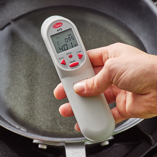 A hand holding a Cooper-Atkins digital infrared thermometer.