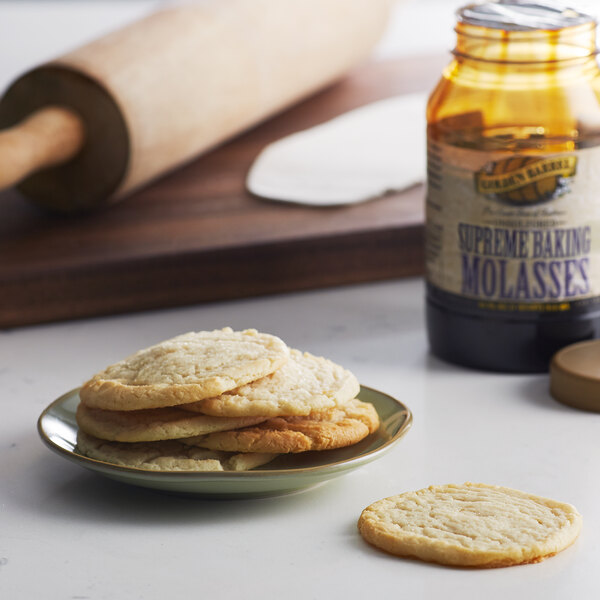 A plate of cookies and a jar of Golden Barrel baking molasses on a table.