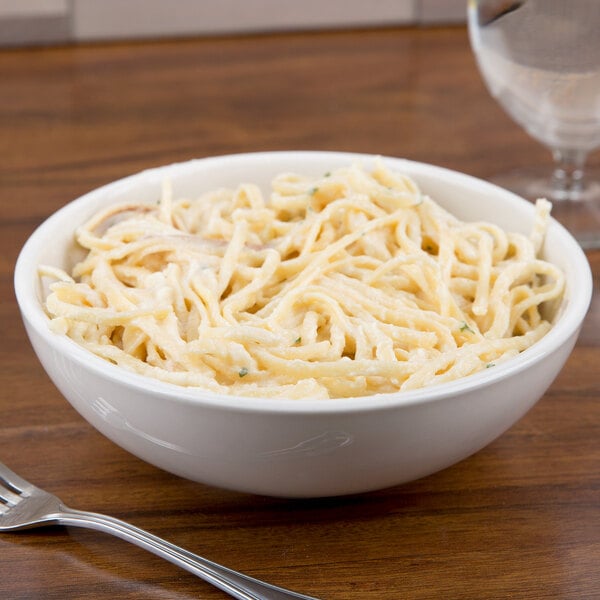A CAC ivory china pasta bowl filled with noodles on a wood table.